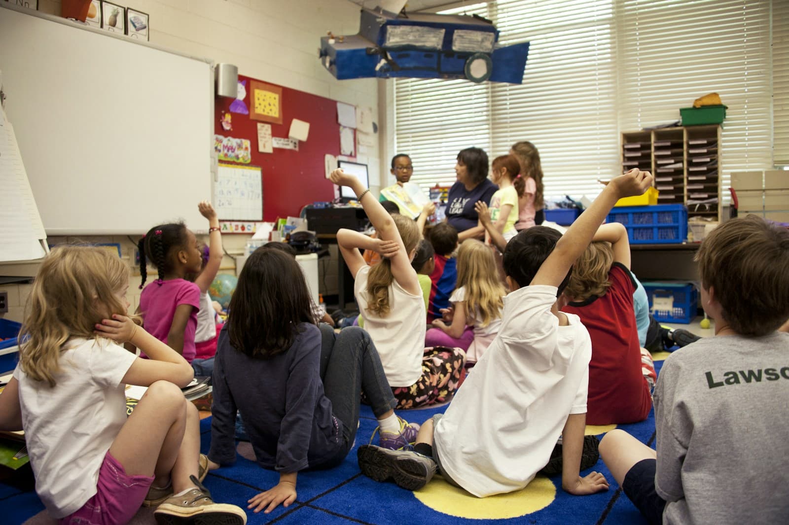 Elementary students raising their hands in a classroom
